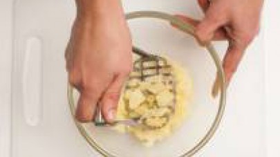 Fate cuocere le patate in abbondante acqua salata, poi scolatele e pelatele. Schiacciatele in una ciotola con uno schiacciapatate a mano.