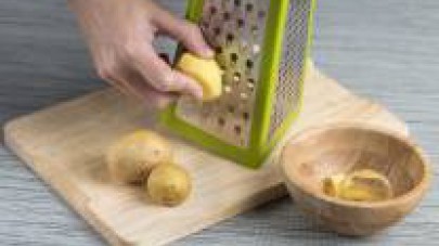 Sbucciate le patate, tagliatele con l'aiuto della grattugia e mettetele da parte. Non lavatele, in questo modo si conserverà l'amido.