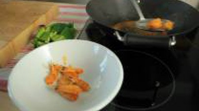 Senza togliere il wok dal fuoco, aggiungete le code dei gamberi