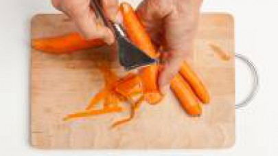 Lavate e pelate le carote.  Tagliate grossolanamente le verdure. 