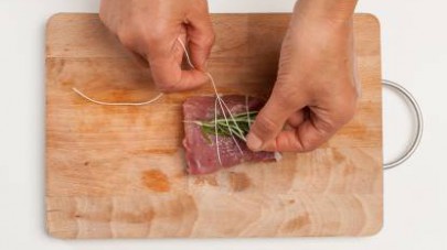 Preparate il filetto di maiale legandolo con un mazzetto di rosmarino e salvia.