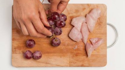 Lavate l’uva e separate gli acini dal raspo; tagliate a cubetti il petto di pollo.