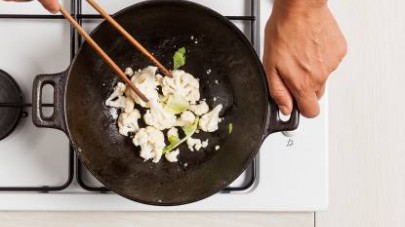Rosolate il cavolfiore in un wok con un cucchiaio di olio extravergine di oliva e uno spicchio di aglio,