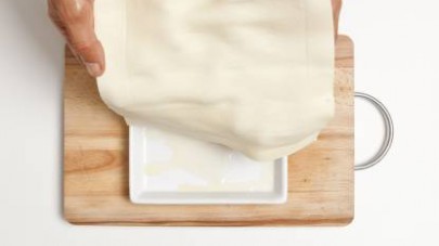 Tagliate la pasta brisé in quattro rettangoli e adagiatela in quattro pirofile monoporzione rivestite di carta da forno. 
